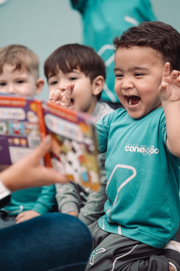 Crianças animadas ouvindo a leitura de um livro com a professora